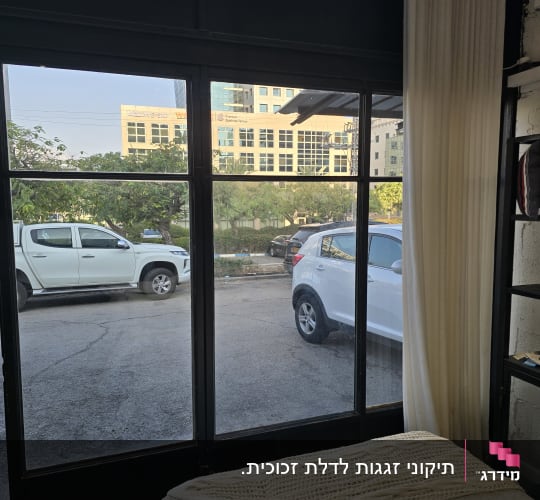 חלון זכוכית גדול עם וילון ומכוניות בחוץ